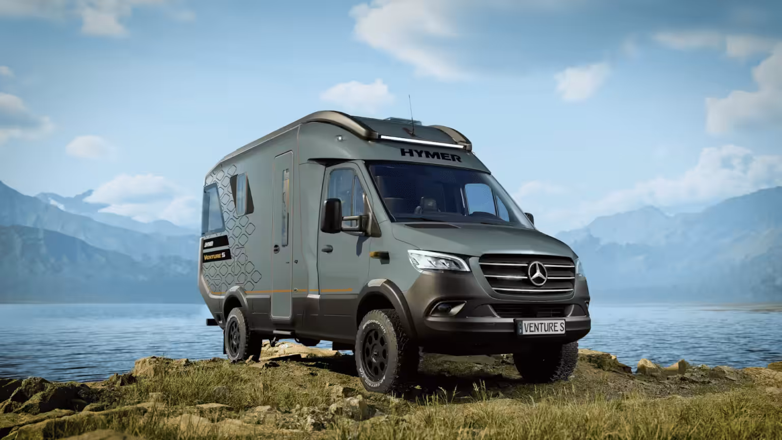 A hymer motorhome on a cliff face overlooking a lake and mountains