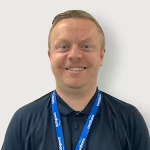 A member of staff, Jake Skyes smiling in a dark blue shirt